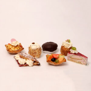 Gesorteerd gebak met chocolade bol, slagroomprogresje, kwarkpunt, vers fruit vlaaitje, kersenflap, appelkaneelmandje